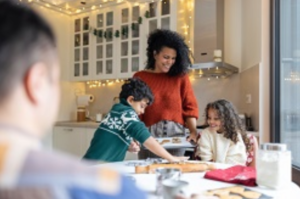 Mother with her daughter and son baking Family Day treats while father looks on