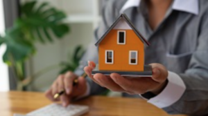 Woman holding a model home and a pen in her hands